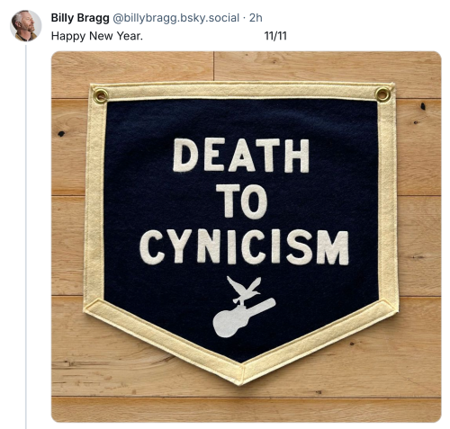 Bluesjy post from Billy Bragg saying "Happy New Year" beneath which is a photo of a fabric patch which reads "DEATH TO CYNICISM" with the logo of a bird flying with a guitar"