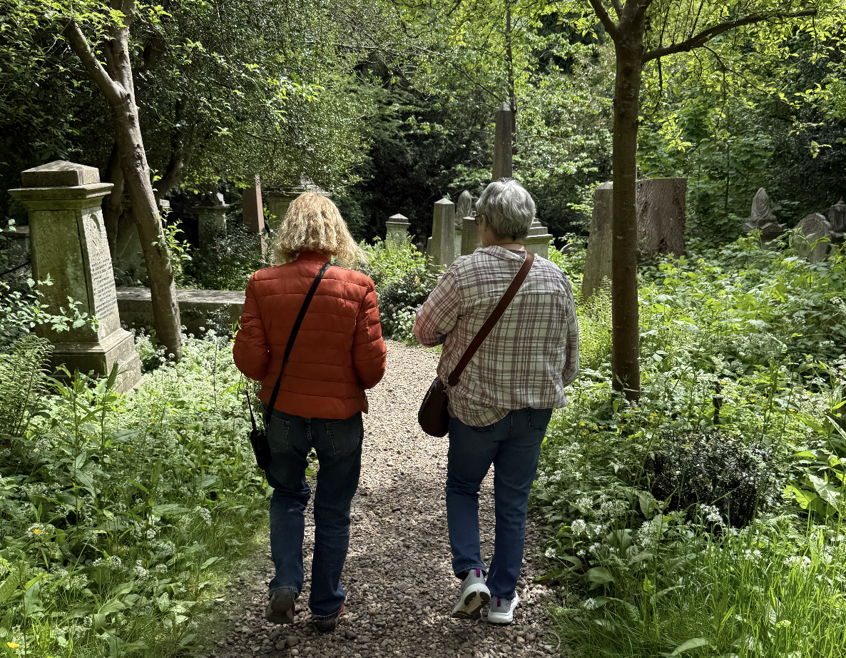 My mom talking to a tour guide in a heavily-wooded Victorian cemetery
