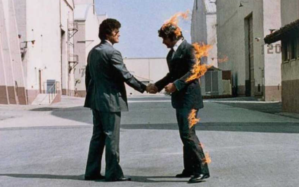 Cover of Pink Floyd's "Wish You Were Here" album, featuring two men who wearing suits, shaking hands. One of them is on fire.
