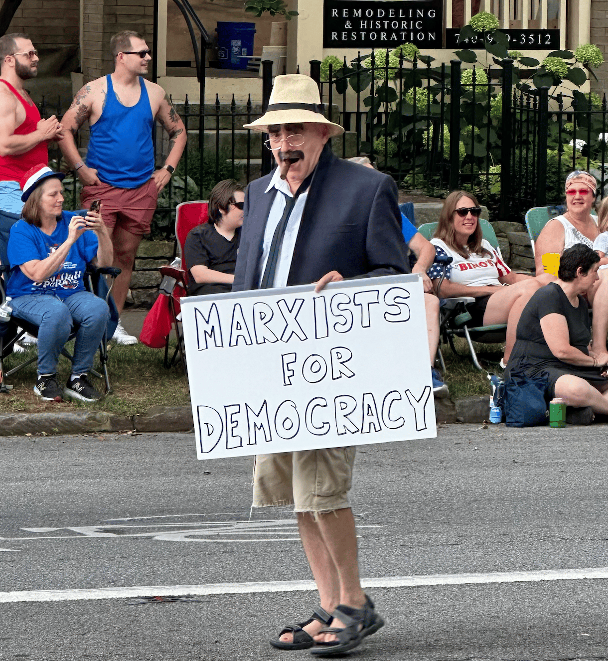 Man dressed as Groucho Marx with a sign that says Marxists for Democracy