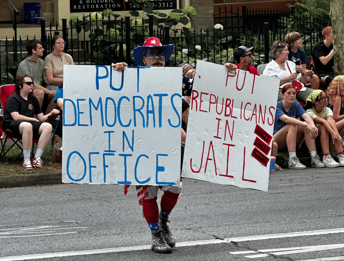 Guy carrying signs: "put democrats in office" and "put republicans in jail"