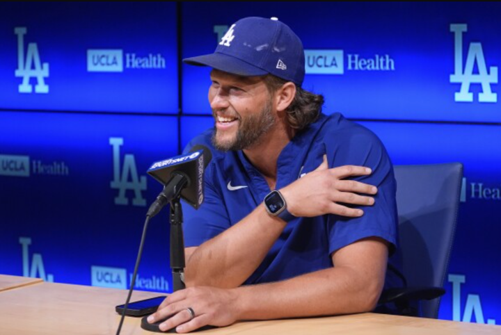 Clayton Kershaw at a table and behind a microphone during a press conference
