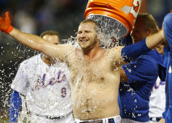 Pete Alonso with no shirt on as teammates pour a Gatorade cooler on him