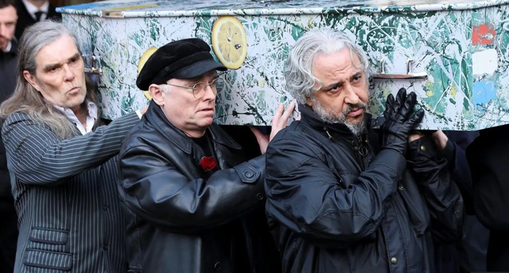 Members of Stone Roses carrying Mani's coffin, which is painted like the first Stone Roses album